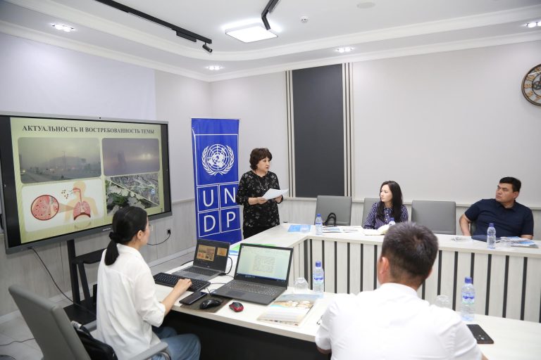 A meeting in a modern conference room with participants and a presentation screen.